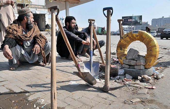 Labourers alongwith their tools sitting on roadside waiting for clients to be hired for work during morning time at Khanna Pull.
