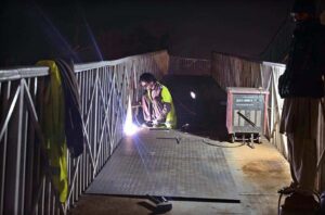 A welder busy in fixing a damaged pedestrian bridge on the Islamabad Expressway.