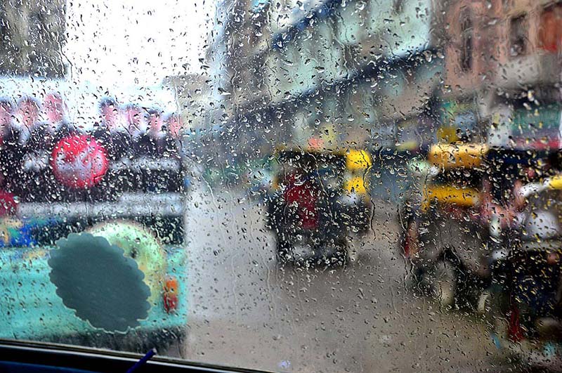 A view of rain drops on windscreen of vehicle during light rain in the city during morning time