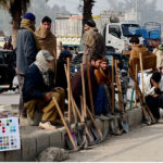 Labourers along with their tools sitting on roadside waiting for clients to be hired for work during morning time
