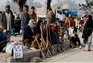 Labourers along with their tools sitting on roadside waiting for clients to be hired for work during morning time
