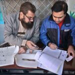 Polling officers searching the name of voter in voter’s list in the polling station during General Election-2024