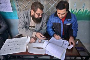 Polling officers searching the name of voter in voter’s list in the polling station during General Election-2024