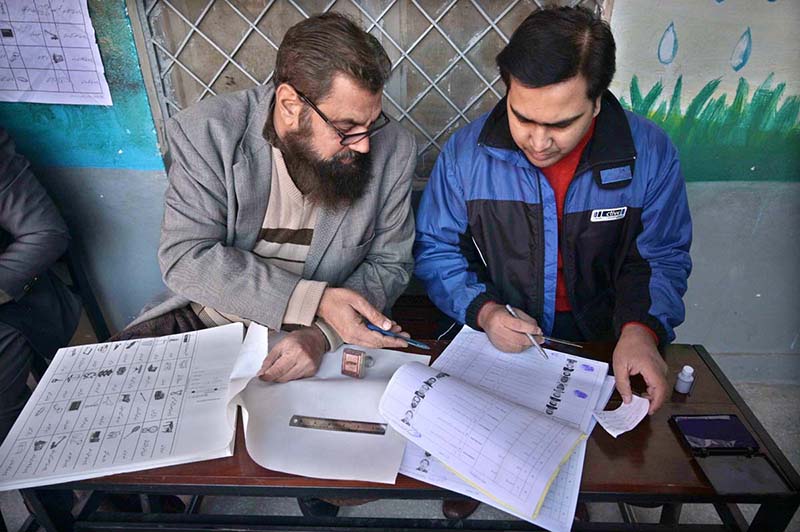 Polling officers searching the name of voter in voter’s list in the polling station during General Election-2024