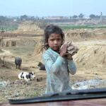 A gypsy young girl on the way while carrying stones in the outskirts of the Federal Capital