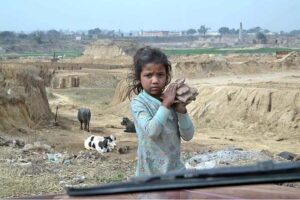 A gypsy young girl on the way while carrying stones in the outskirts of the Federal Capital
