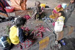Women along with children busy in making flower bouquet for selling while sitting at roadside.