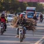 A motorcyclist on the way carrying bundle of wood sticks to be used for cooking purposes on the Islamabad Expressway.