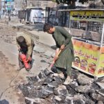 Labourers busy in repairing work of road at Commercial Market during construction work.
