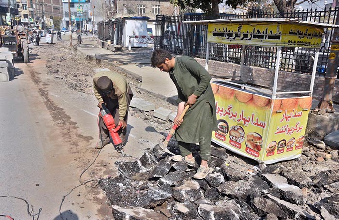 Labourers busy in repairing work of road at Commercial Market during construction work.