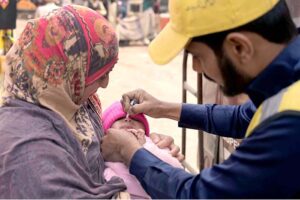 A health worker administering polio drops to child at Nori Gate