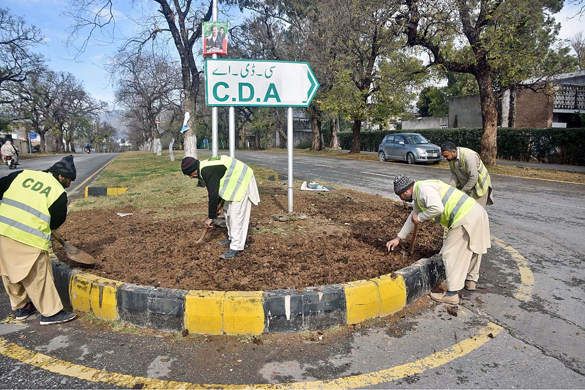 CDA workers busy in preparing center path of road for plantation in the Federal Capital.