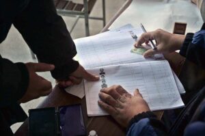Polling officers searching the name of voter in voter’s list in the polling station during General Election-2024