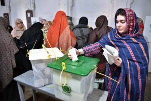 A woman casts her vote at a polling station during General Elections-2024.
