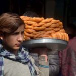 Youngster selling and displaying traditional sweet item donuts to attract the customers at Khyber Bazar.