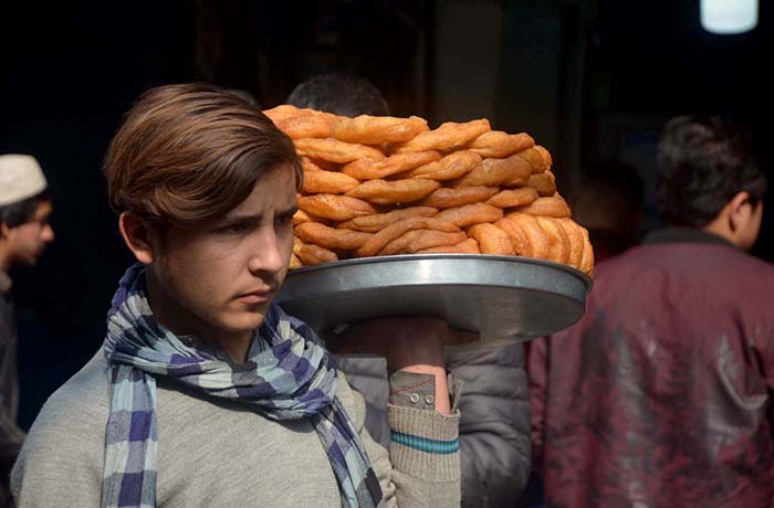 Youngster selling and displaying traditional sweet item donuts to attract the customers at Khyber Bazar.