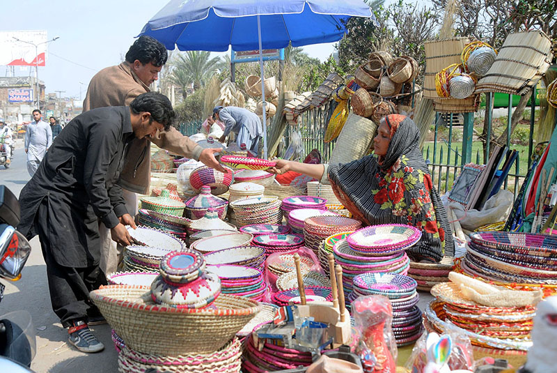 Woman vendor displaying and selling handmade household items to earn a livelihood at roadside setup