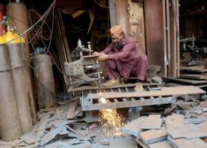 A blacksmith is busy at his workplace cutting large pieces of iron and making molds.