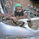 A craftsman repairs car bumpers in his workshop.