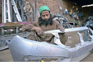 A craftsman repairs car bumpers in his workshop. 