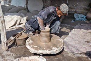 Craftsmen busy in preparing clay made pots at his workplace. 