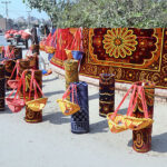 Vendor displaying carpet and swing for children to attract the customers at roadside setup.