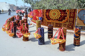 Vendor displaying carpet and swing for children to attract the customers at roadside setup.