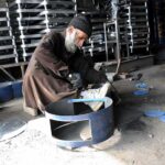 Worker busy in connecting parts of the traditional fire stove at his workplace
