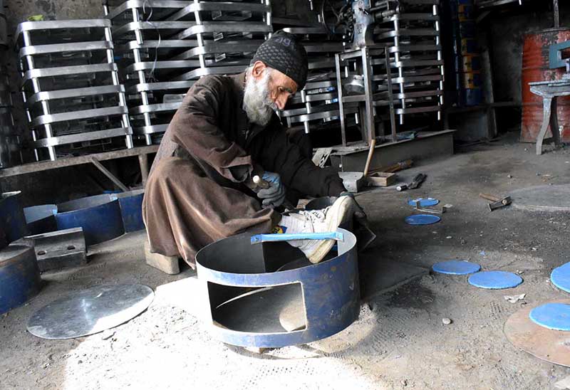 Worker busy in connecting parts of the traditional fire stove at his workplace