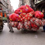 Laborers carrying quilts on his delivery cart for selling purpose in the local market.