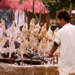 A vendor busy preparing chicken sajji for customers at Local Park.