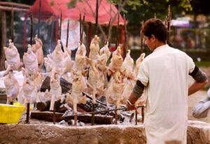 A vendor busy preparing chicken sajji for customers at Local Park. 