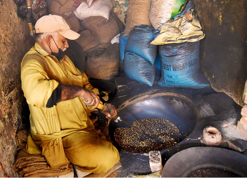 A worker busy in roasting grams for customers at his workplace