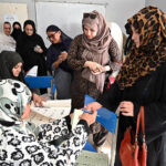 An election official marks ink the thumb of a woman at a polling station during General Elections 2024