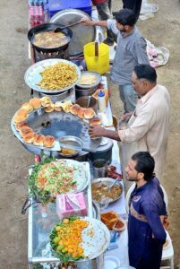 Vendors displaying the traditional food items chips and Burgers to attract the customers outside road at Latifabad.