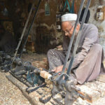 A carpenter busy in making part of a traditional bed (charpai) at his workplace.