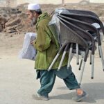An elderly vendor carrying plastic chairs for selling at Jail Road