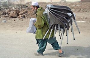 An elderly vendor carrying plastic chairs for selling at Jail Road