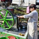 A vendor extracting sugarcane juice at his roadside setup.