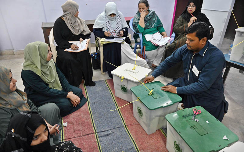 An election official marks ink the thumb of a woman at a polling station during General Elections 2024