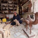 Vendor busy in making wooden decoration items at his workplace.