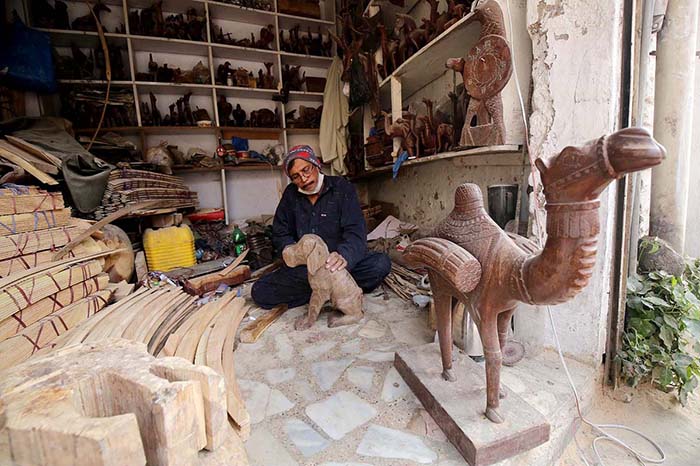 Vendor busy in making wooden decoration items at his workplace.