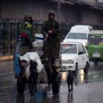 Gypsy people on the way on their donkey cart while protecting themselves with rain cover during rain in the Provincial Capital.