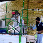 A vendor extracting sugarcane juice at his roadside setup in Federal Capital