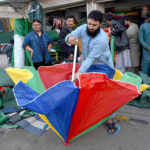 A vendor displaying colorful umbrella to attract customers at his workplace