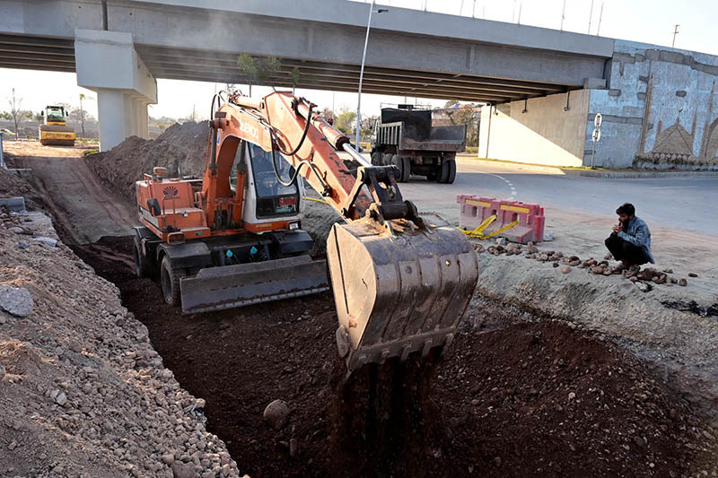 Labourer busy in construction work of Park Road with the help of heavy machinery during development work in the city