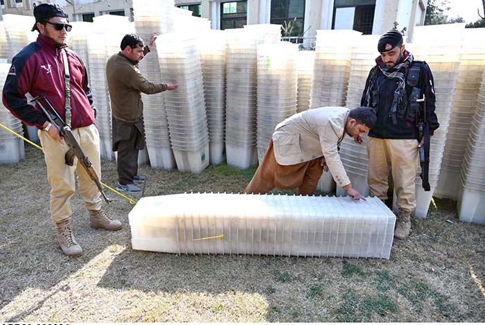 Workers of the Election Commission Office sorting ballot boxes to be sent to polling stations for the upcoming General Elections-2024 at Qayyum Sports Complex.