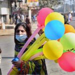 A woman vendor displaying balloons to attract the customers.