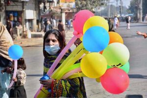 A woman vendor displaying balloons to attract the customers.