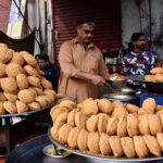A vendor is selling the traditional food item “Laddu Peethi” to the customers on his roadside setup at local market
